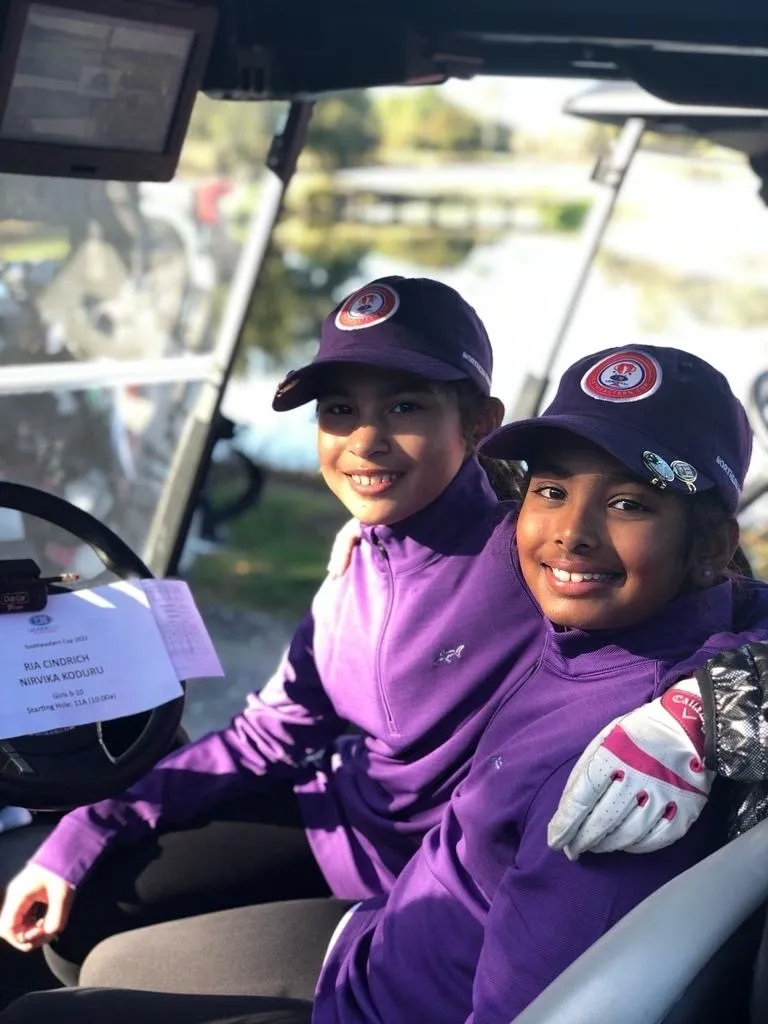 Two young boys in purple jackets and hats.