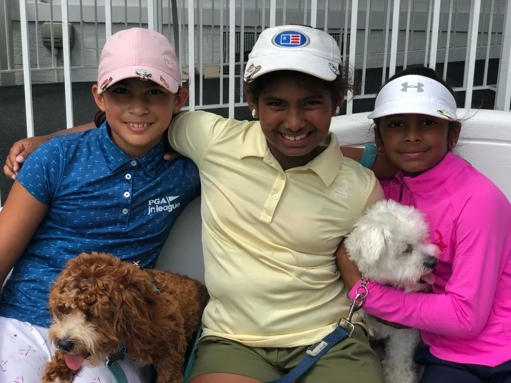 Three young people are holding their dogs.